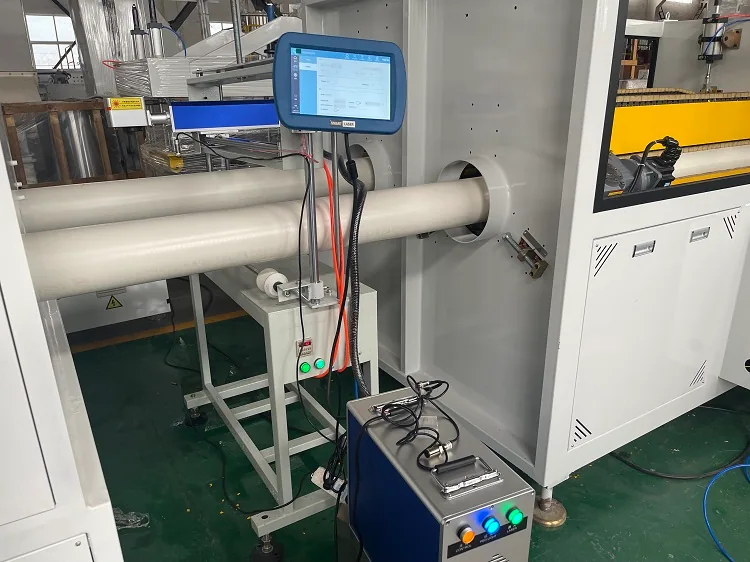 Laser marking head positioned beside PVC pipe for online coding